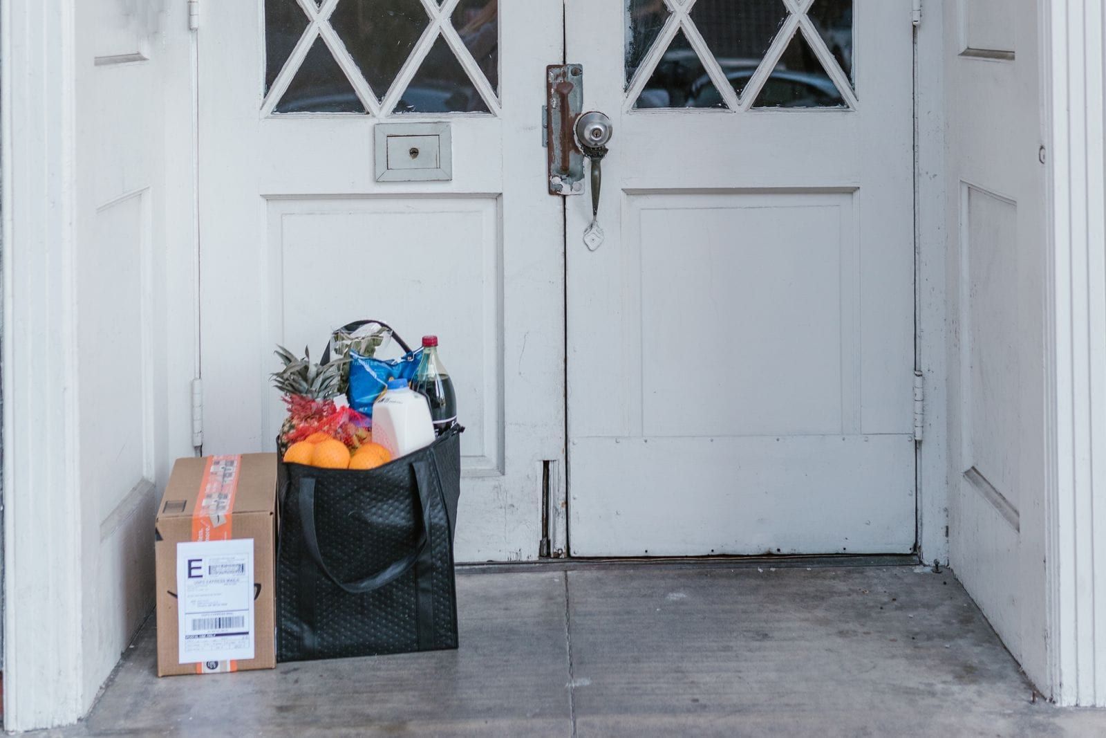 A bag of groceries and a parcel left at a front door