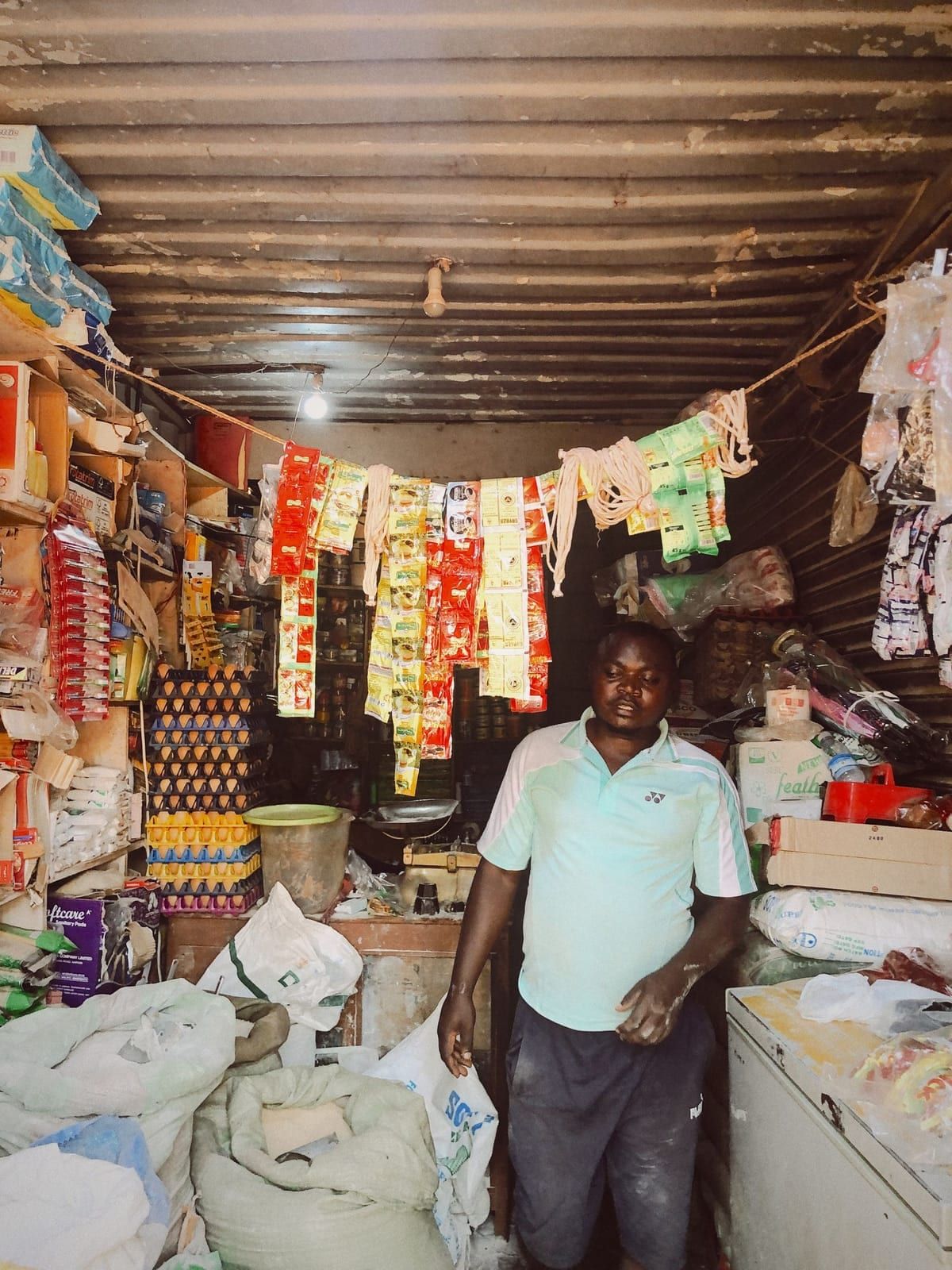 A shopkeeper standing in his small, well-stocked shop